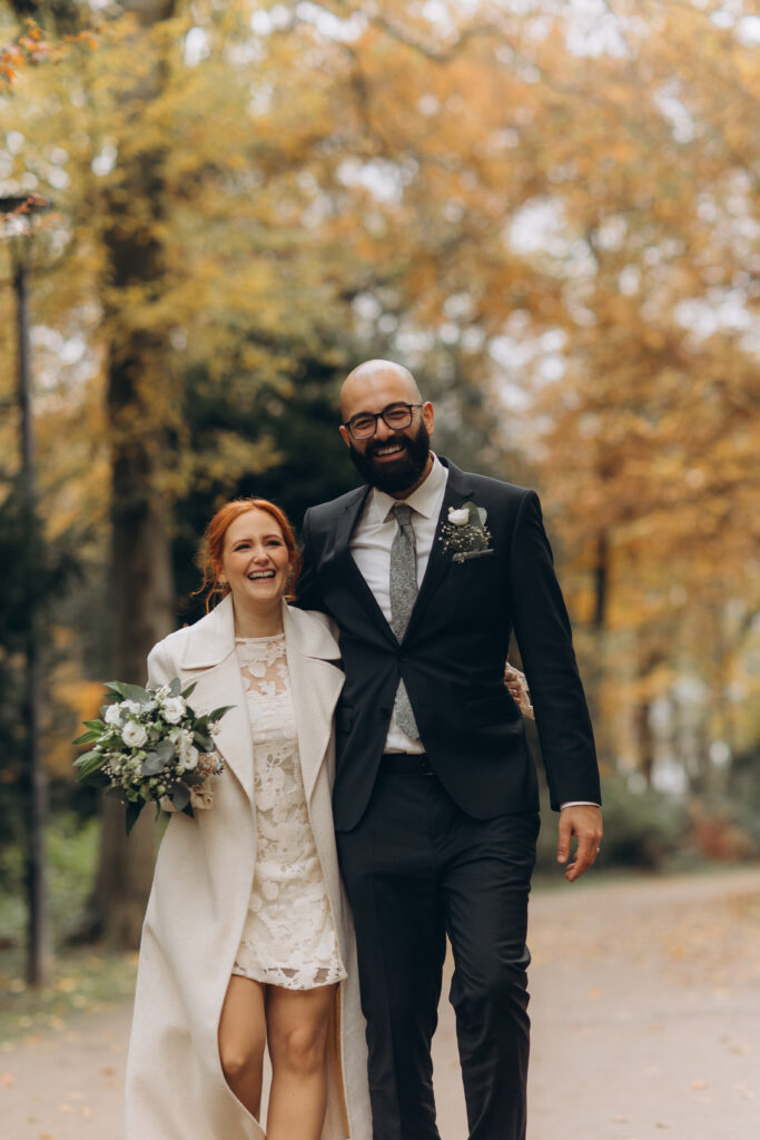 Lächelndes Hochzeitspaar bei goldenem Sonnenuntergang im Herbst, Braut in elegantem Kleid, intime und natürliche Hochzeitsfotografie.