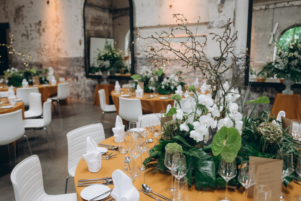 Elegante Tischdekoration mit weißen Blüten, tropischem Grün und Lichterketten bei einer Hochzeitsfeier im Harbour Club Köln.